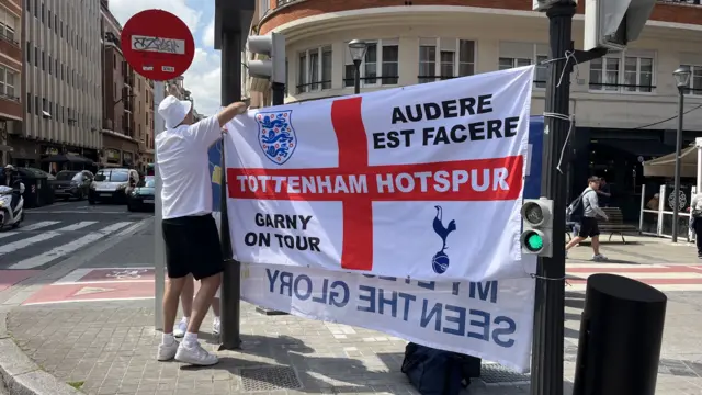 Fan putting up a Tottenham flag in a street in Bilbao
