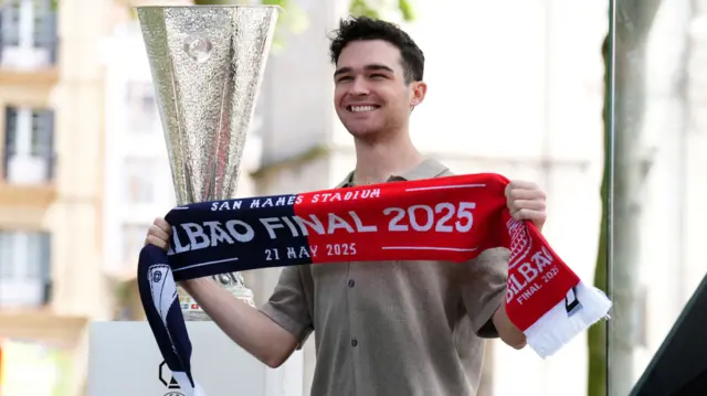 A fan poses for a picture with a half and half scarf