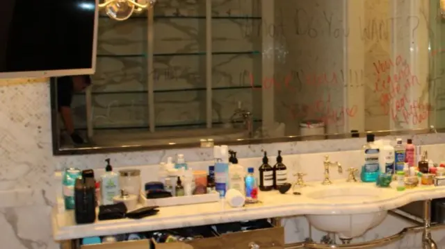 Messages written on a bathroom mirror with several beauty products scattered across the bench