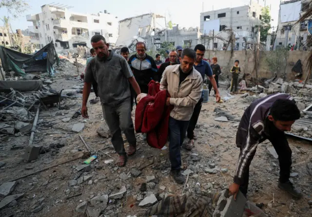 Palestinians carry a body at the site of an Israeli strike on a house, in Jabalia, northern Gaza Strip May 21, 2025