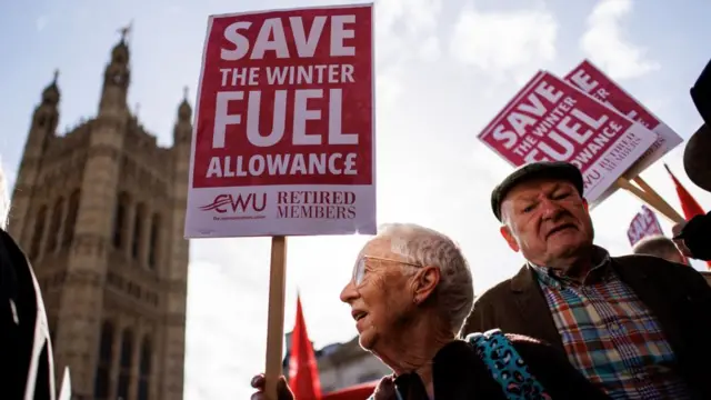 Protesters hold placards while campaigning for the reversal of the winter fuel payment cuts to pensioners, which is proposed by the British government, at Old Palace Yard, in London, Britain