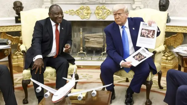 Trump holds up news articles related to violence in South Africa during a meeting with South Africa's President Cyril Ramaphosa in the Oval Office