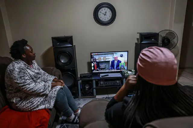 Two women watch a TV broadcast of a bilateral meeting between South African President Cyril Ramaphosa and US President Donald Trump at their home in Silverton, Pretoria