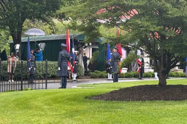 US service members carrying flags lined up outside the White House