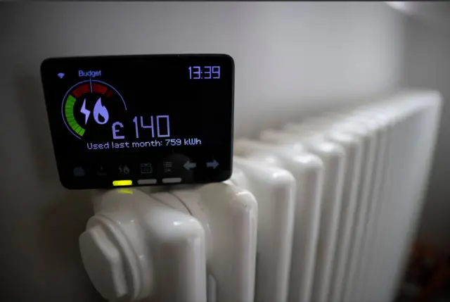 A smart energy meter, used to monitor gas and electricity use, is pictured with a radiator in a home.