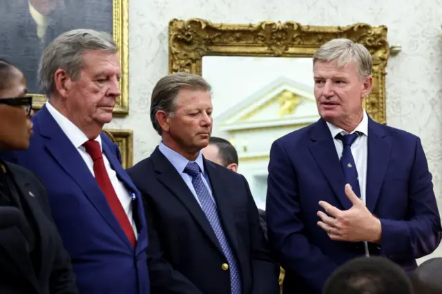 Golfer Retief Goosen listens as Ernie Els speaks in the Oval Office