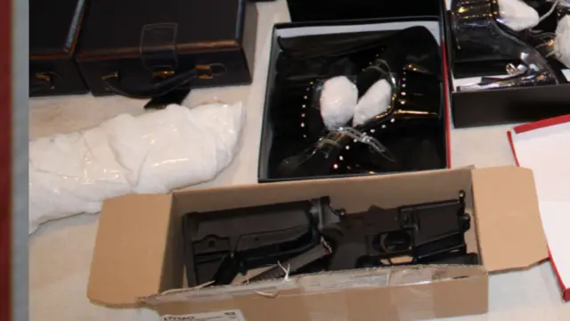 Gun parts in a box, next to high heels in a box