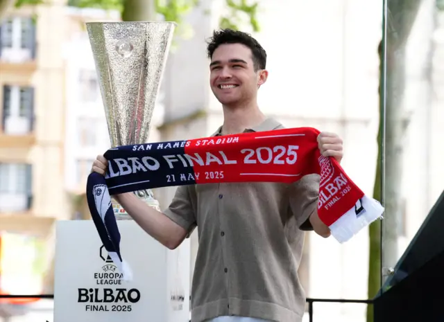 Fan poses with a scarf and trophy in Bilbao