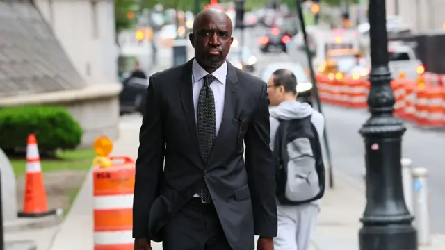 Attorney Xavier Donaldson walks towards the camera. Traffic cones can be seen behind him with the background blurred.