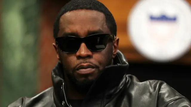 Sean "Diddy" Combs wearing a black leather jacket and large black sunglasses