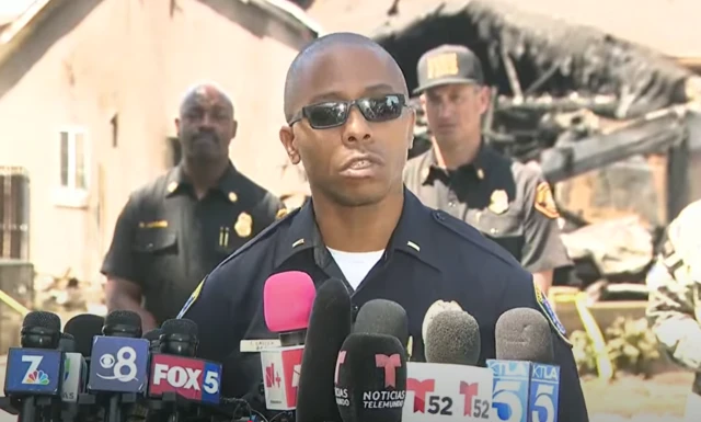 Officer Easter speaking at a press conference in front of a damaged house