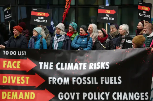 climate change protesters holding a poster demanding government action