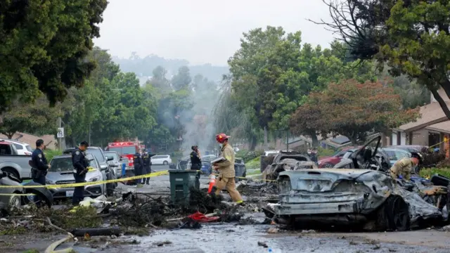 A street with burnt out cars and emergency workers