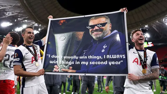 Sergio Reguilon and James Maddison holding a banner of Ange Postecoglou after Tottenham win the 2025 Europa League final