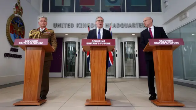 The three men standing behind wood lecterns in a line