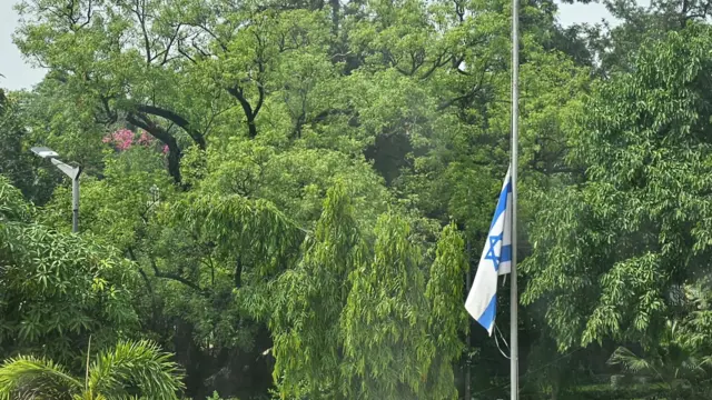 Lowered Israeli flag against a backdrop of tropical trees