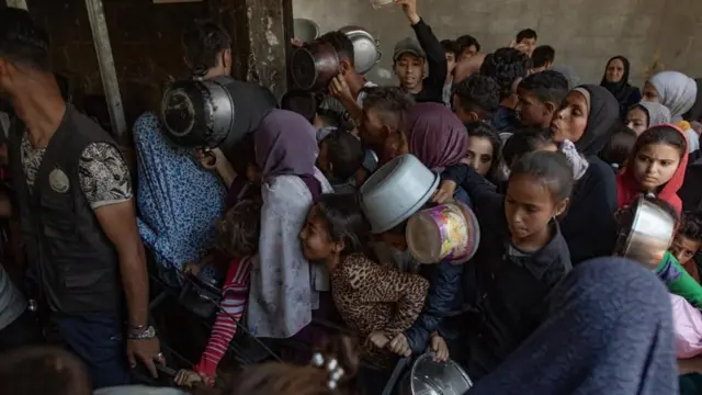 Hundreds of displaced Palestinians gather outside the Sokar Charity Kitchen in Gaza City to receive limited food rations,21 May, 2025