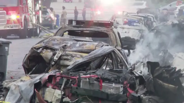 A completely burnt out car with smoke coming out of it