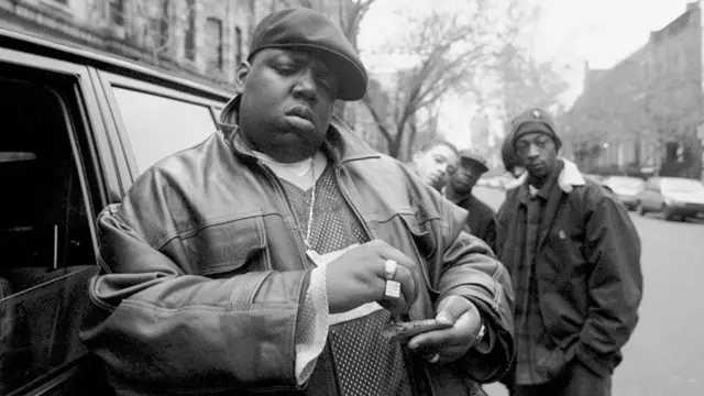 American rapper Notorious B.I.G., aka Biggie Smalls, aka Chris Wallace (1972 - 1997), rolls a cigar outside his mother's house in Brooklyn,