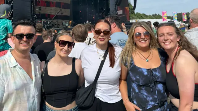 Freya Burns stands with four friends and they are all smiling for the camera. They are stood in the crowd in front of a stage at Big Weekend.