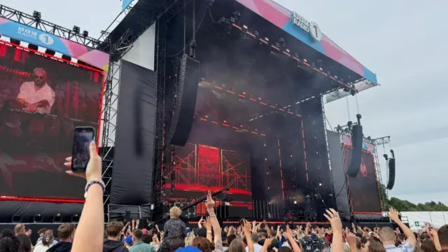 James Hype takes the main stage. A screen shows the DJ, with a large crowd around the stage.