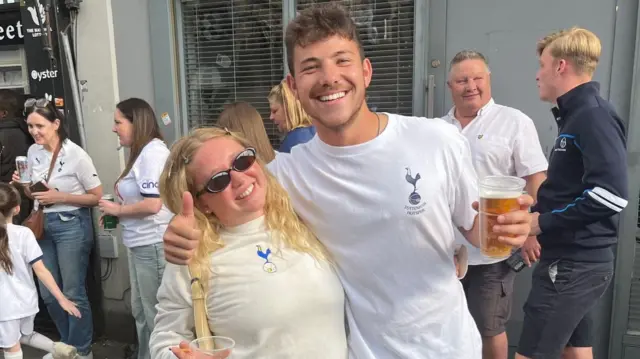 Emma and Dillon are seen smiling with their arms around each other both with a beer in hand