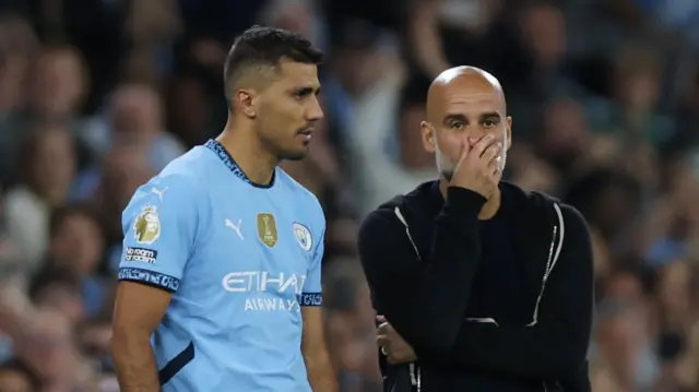 Manchester City coach Pep Guardiola prepares to bring on midfielder Rodri against Bournemouth