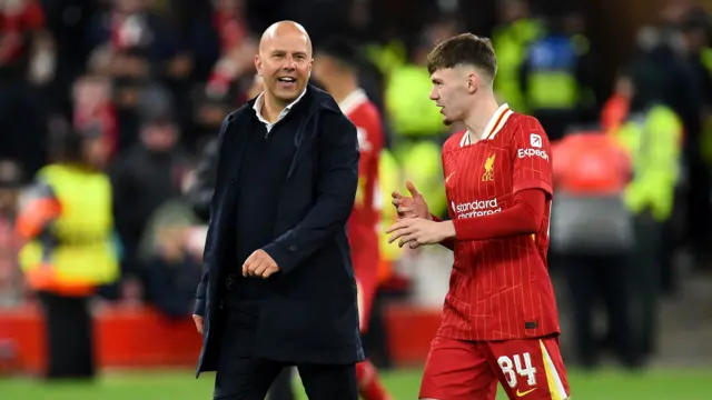 Liverpool boss Arne Slot smiles while talking to right-back Conor Bradley