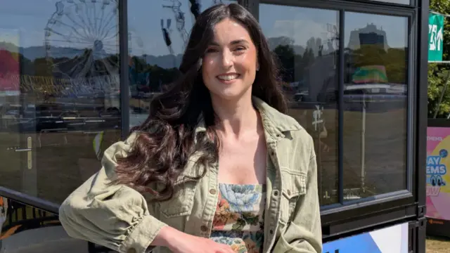 Vicky Hawkesworth smiles at the camera. She is wearing a light green denim jacket. She has long brown hair.