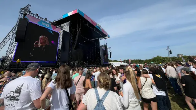 A crowd of people stand in front of the Main Stage at Big Weekend. Natasha Bedingfield is singing on the stage.