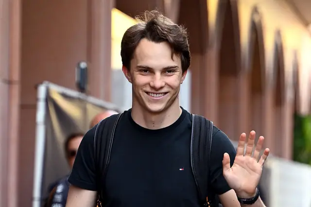 Oscar Piastri waves in the Monaco paddock