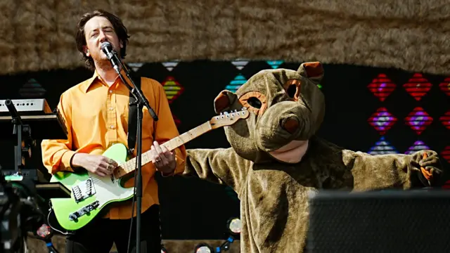 The Wombats' singer on stage with a giant Wombat costume behind him