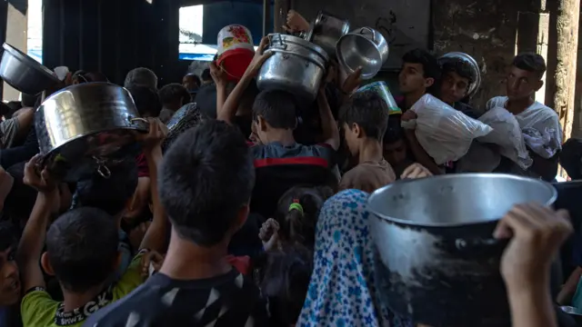Gazans hold pots above their heads as they try to get aid