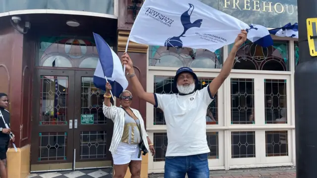 A woman and man are seen waving their Spurs flag high