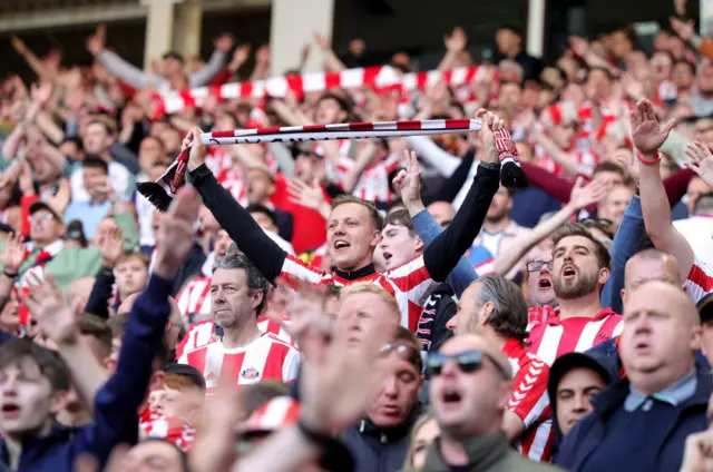 Sunderland fans during the play-off semi final, second leg match at the Stadium of Light. It is a close-up of the fans with many of them wearing red and white Sunderland shirts and holding scarves above their heads