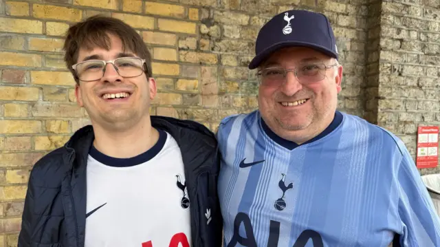 Owen (L) and Martin Doody (R) pose for a picture on the train platform, both are wearing Spurs jerseys, one in white the other one in light blue