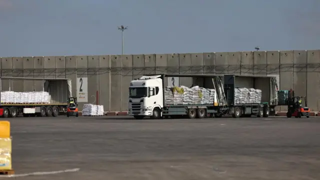Trucks carrying aid wait to enter the Gaza Strip at the Kerem Shalom crossing