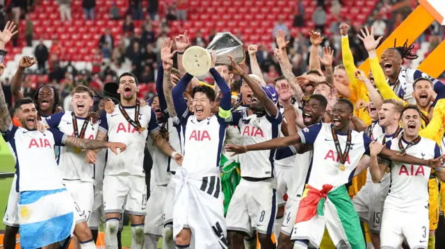 Son Heung-min lifts the Europa League trophy, surrounded by his team-mates, after Tottenham win the 2025 final