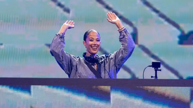 Singer and songwriter Jazzy on the New Music Stage with her hands up in the air