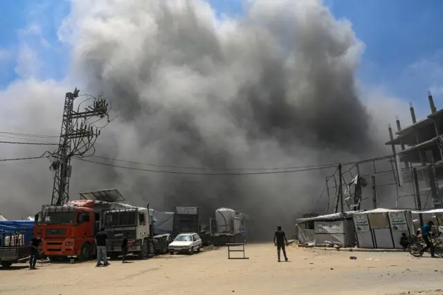 A Palestinian walks in the middle of a road as smoke rises following an Israeli airstrike west of Gaza City, in Gaza Strip, 23 May 2025