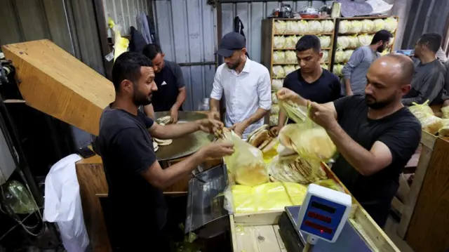 Palestinian workers pack bread in a bakery that returned to operation after being closed due to a flour shortage, in Deir al-Balah, in the central Gaza Strip, 22 May