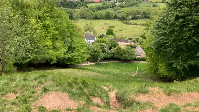 A view from the top of Cooper's Hill. It is a steep drop down where a road and a few houses are.