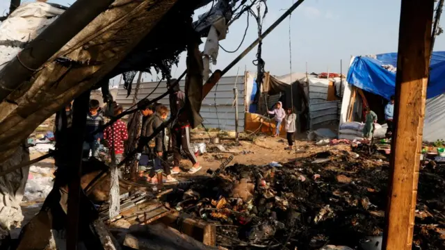Palestinians inspect the site of an Israeli strike on a tent camp housing displaced people, in Al-Mawasi area