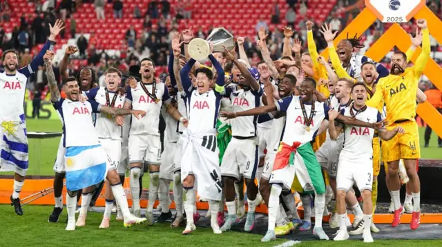 Tottenham Hotspur players celebrate their Europa League win on the pitch, captain Son Heung-min at the centre lifting the trophy
