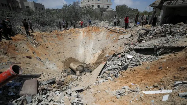 A large crater surrounded by rubble following an air strike.