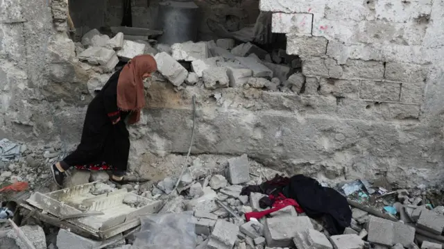 A woman walks amid rubble following a strike in the city of Jabalia
