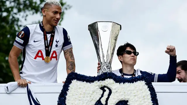 Son Heung-Min holds the Europa League trophy, alongside Tottenham Hotspur's Brazilian forward #09 Richarlison, during an open-top bus parade
