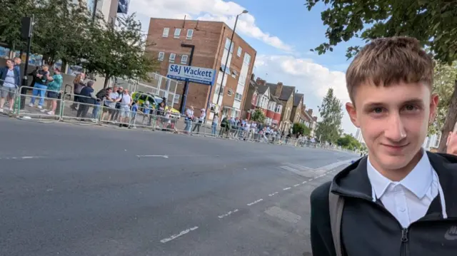 James Adams smiles for the camera while stood behind a barricade on a road marked out for the Spurs parade.