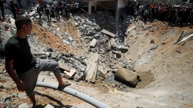 A man peers over a large crater filled with debris.