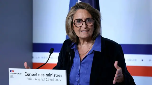 Sophie Primas speaks at podium wearing jeans blouse and dark blazer